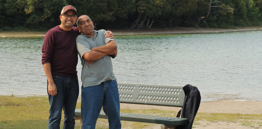 Image of two men standing by a bench and water